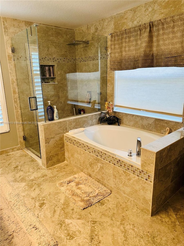 bathroom with a bath, a shower stall, a textured ceiling, and healthy amount of natural light