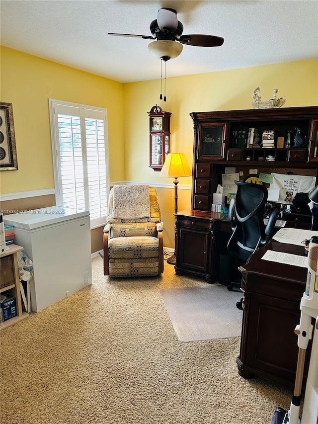 office area with a ceiling fan and carpet flooring