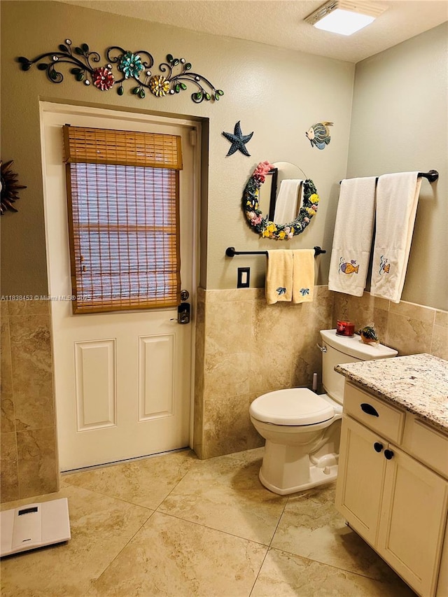 bathroom featuring tile walls, tile patterned flooring, vanity, and a wainscoted wall
