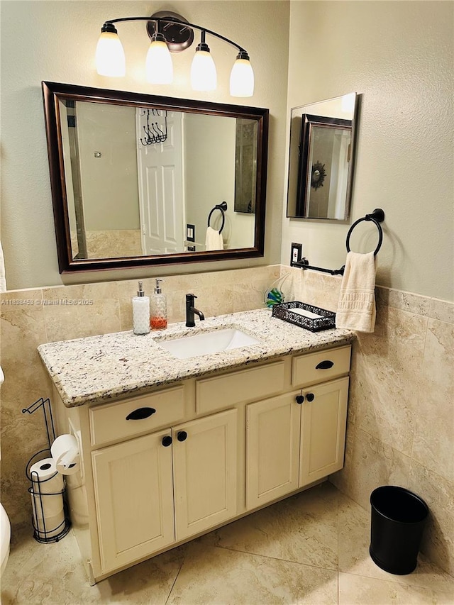 bathroom featuring tile walls, vanity, and wainscoting