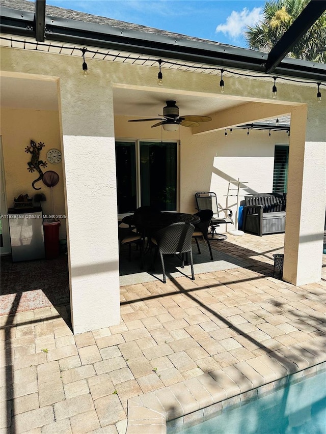 view of patio featuring ceiling fan, outdoor dining area, an outdoor pool, and glass enclosure