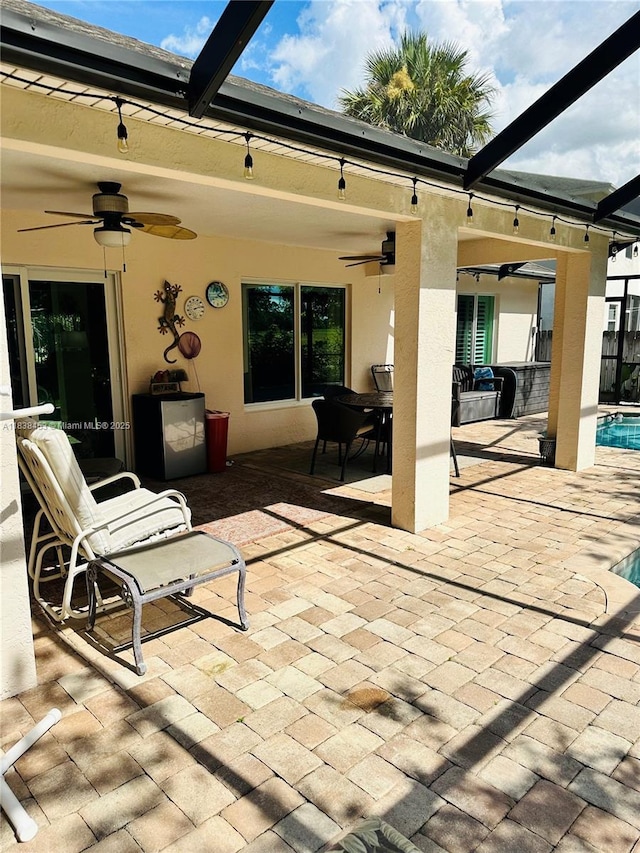 view of patio / terrace with ceiling fan, an outdoor pool, and glass enclosure
