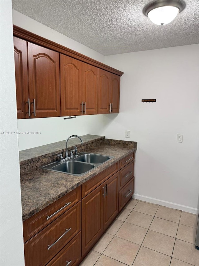 8560 N Sherman Cir Unit 105, Miramar, FL 33025 - kitchen featuring dark countertops, a textured ceiling, light tile patterned floors, and brown cabinetry