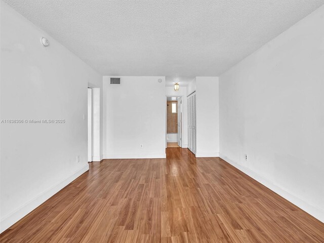 1170 NE 191st St Unit 24, Miami, FL 33179 - spare room featuring a textured ceiling, light wood-type flooring, and a smoke detector