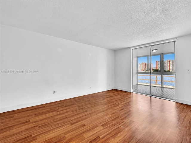 1170 NE 191st St Unit 24, Miami, FL 33179 - spare room featuring a textured ceiling, wood finished floors, and floor to ceiling windows