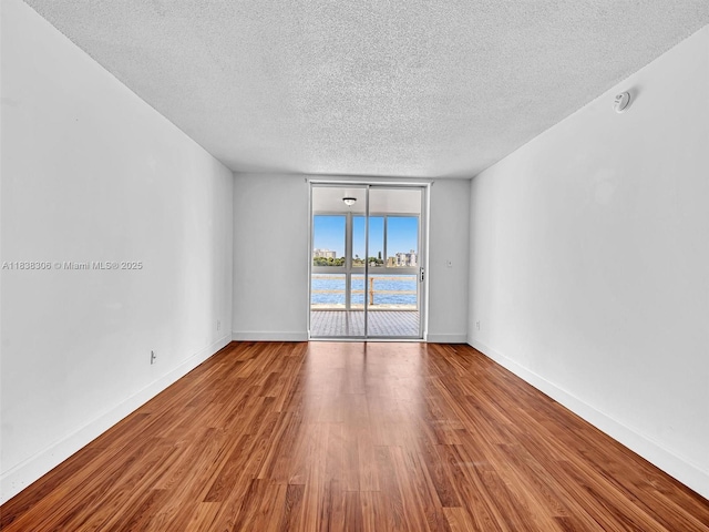 1170 NE 191st St Unit 24, Miami, FL 33179 - spare room with a textured ceiling, wood finished floors, a water view, expansive windows, and a smoke detector