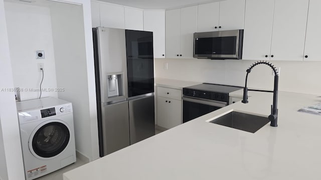 1450 Brickell Bay Dr Unit 1402, Miami, FL 33131 - kitchen featuring stainless steel appliances, washer / clothes dryer, light countertops, and white cabinetry