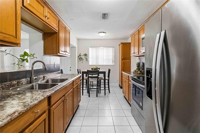 5723 NW 86th Ave, Tamarac, FL 33321 - kitchen featuring appliances with stainless steel finishes, brown cabinetry, and light tile patterned flooring