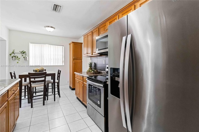 5723 NW 86th Ave, Tamarac, FL 33321 - kitchen with stainless steel appliances, brown cabinetry, light tile patterned flooring, and light countertops