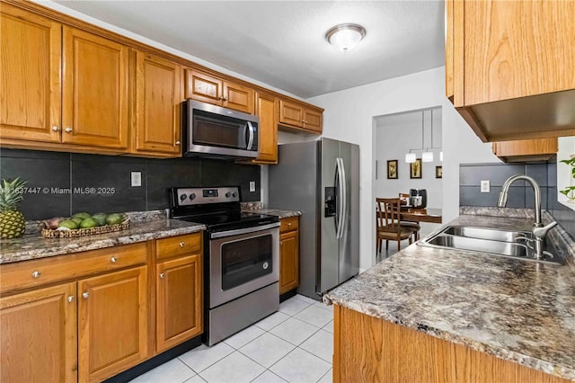 5723 NW 86th Ave, Tamarac, FL 33321 - kitchen featuring appliances with stainless steel finishes, tasteful backsplash, brown cabinets, light tile patterned floors, and dark stone countertops