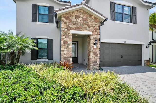 8036 NW 78th St, Tamarac, FL 33321 - view of front facade with stone siding, an attached garage, stucco siding, and decorative driveway