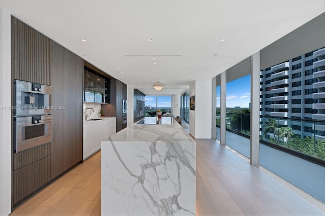 10203 Collins Ave Unit 701, Bal Harbour, FL 33154 - kitchen featuring modern cabinets, light wood-style flooring, a center island, light stone countertops, and open floor plan