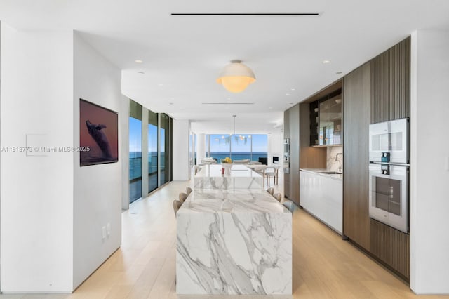 10203 Collins Ave Unit 701, Bal Harbour, FL 33154 - kitchen with modern cabinets, a center island, light wood-style flooring, expansive windows, and pendant lighting