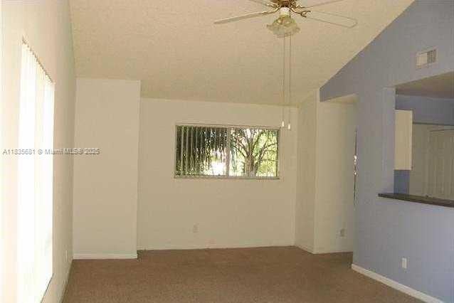 3421 NW 44th St Unit 103, Oakland Park, FL 33309 - empty room featuring vaulted ceiling, ceiling fan, and carpet flooring