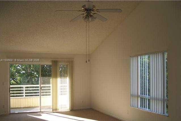 3421 NW 44th St Unit 103, Oakland Park, FL 33309 - empty room featuring a ceiling fan, vaulted ceiling, and carpet floors