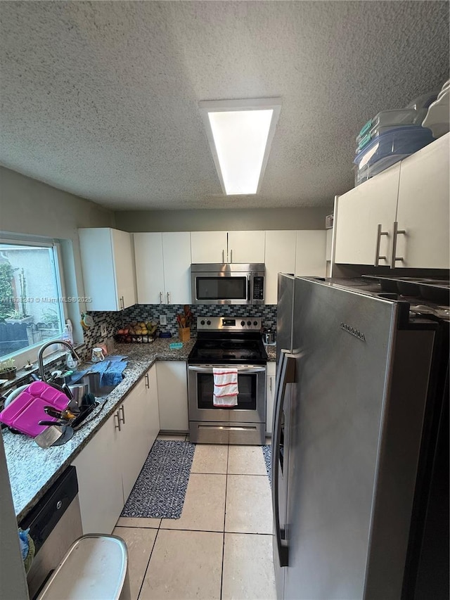 10726 SW 147th Pl, Miami, FL 33196 - kitchen with stainless steel appliances, a textured ceiling, white cabinetry, backsplash, and light tile patterned floors
