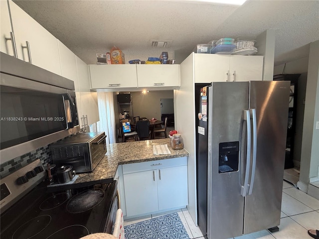 10726 SW 147th Pl, Miami, FL 33196 - kitchen featuring appliances with stainless steel finishes, a textured ceiling, light tile patterned floors, white cabinetry, and backsplash