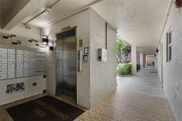 2400 NE 10th St Unit 104, Pompano Beach, FL 33062 - view of home's community featuring mail area, a textured wall, and a textured ceiling