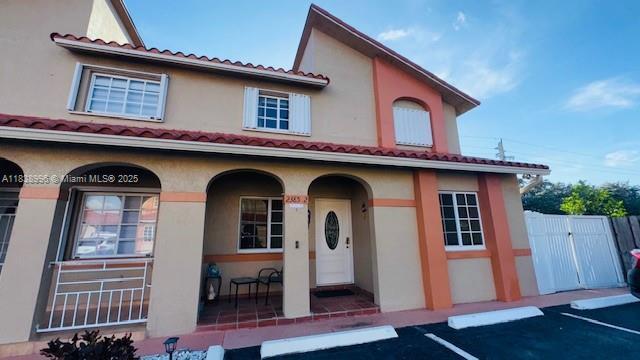 2385 W 69th St Unit 2385-B, Hialeah, FL 33016 - mediterranean / spanish-style house featuring a porch, a gate, uncovered parking, and stucco siding
