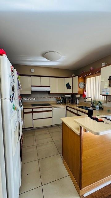 2385 W 69th St Unit 2385-B, Hialeah, FL 33016 - kitchen featuring white appliances, a peninsula, white cabinets, light tile patterned floors, and under cabinet range hood