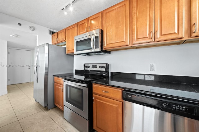 770 Claughton Island Dr Unit 1915, Miami, FL 33131 - kitchen featuring appliances with stainless steel finishes, light tile patterned floors, brown cabinetry, a textured ceiling, and rail lighting