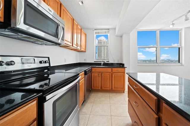 770 Claughton Island Dr Unit 1915, Miami, FL 33131 - kitchen featuring appliances with stainless steel finishes, rail lighting, brown cabinetry, a textured ceiling, and light tile patterned floors