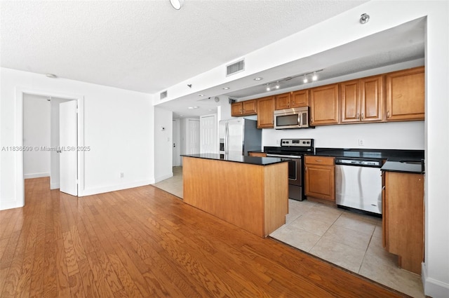 770 Claughton Island Dr Unit 1915, Miami, FL 33131 - kitchen with appliances with stainless steel finishes, dark countertops, a kitchen island, brown cabinets, and a textured ceiling