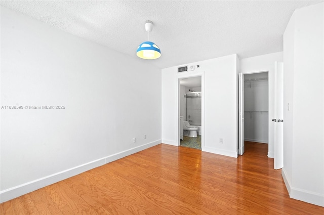 770 Claughton Island Dr Unit 1915, Miami, FL 33131 - unfurnished bedroom featuring wood finished floors, a spacious closet, a textured ceiling, and connected bathroom