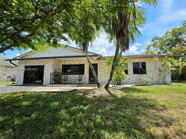 10120 NW 71st Pl, Tamarac, FL 33321 - back of house with stone siding, a lawn, and a porch