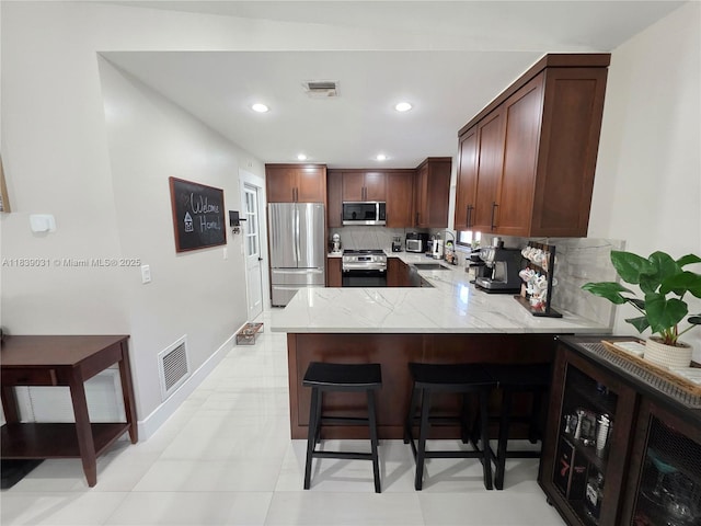 10120 NW 71st Pl, Tamarac, FL 33321 - kitchen with appliances with stainless steel finishes, a peninsula, tasteful backsplash, a kitchen breakfast bar, and light stone countertops