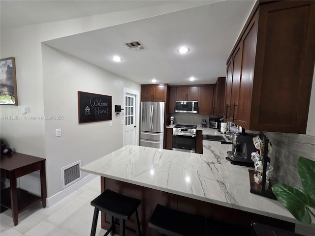 10120 NW 71st Pl, Tamarac, FL 33321 - kitchen featuring stainless steel appliances, a peninsula, decorative backsplash, light stone countertops, and recessed lighting