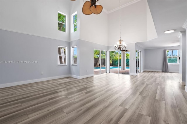14834 SW 140th St, Miami, FL 33196 - unfurnished living room with a chandelier, ceiling fan, a towering ceiling, light wood-style floors, and ornamental molding