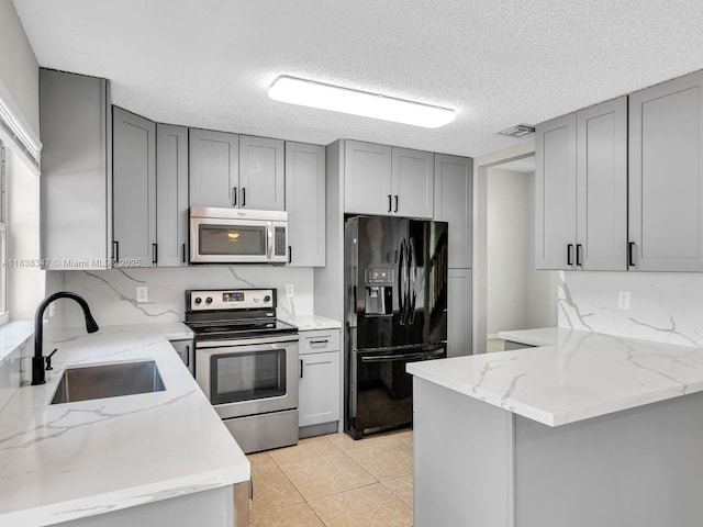 18232 SW 5th St, Pembroke Pines, FL 33029 - kitchen featuring stainless steel appliances, gray cabinets, light stone countertops, a peninsula, and tasteful backsplash