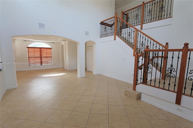 3001 SW 156th Ave, Miami, FL 33185 - unfurnished living room featuring arched walkways, tile patterned floors, a towering ceiling, and stairway