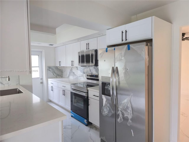 1141 SW 8th Ter, Fort Lauderdale, FL 33315 - kitchen featuring stainless steel appliances, backsplash, white cabinetry, light stone countertops, and light marble finish flooring
