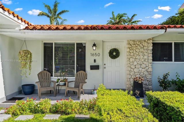 1650 SW 17th St, Miami, FL 33145 - doorway to property featuring a tiled roof, stucco siding, a porch, and stone siding
