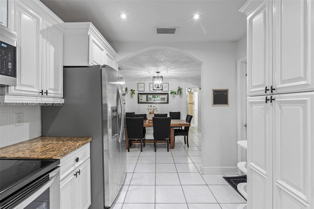 1650 SW 17th St, Miami, FL 33145 - kitchen with arched walkways, white cabinets, backsplash, light tile patterned flooring, and stainless steel microwave