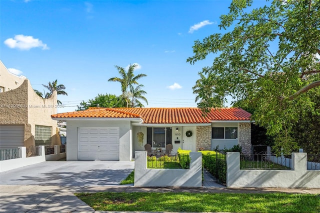 1650 SW 17th St, Miami, FL 33145 - mediterranean / spanish-style home featuring a tiled roof, a garage, a fenced front yard, and stucco siding