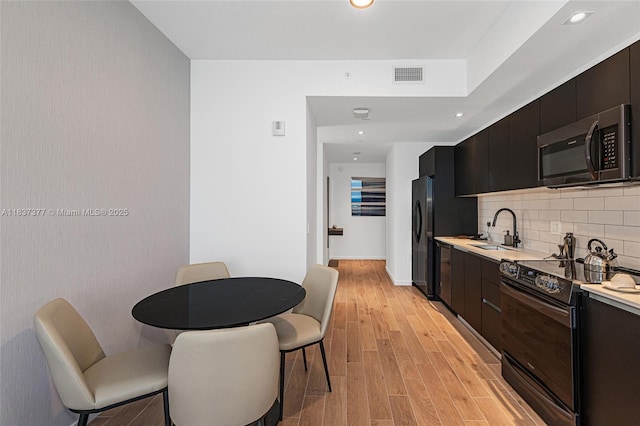 398 NE 5th St Unit 3711, Miami, FL 33132 - kitchen featuring stainless steel microwave, black electric range, light countertops, tasteful backsplash, and light wood-type flooring