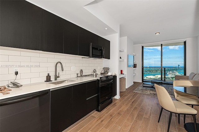 398 NE 5th St Unit 3711, Miami, FL 33132 - kitchen with dark cabinetry, black electric range oven, stainless steel dishwasher, backsplash, and light countertops