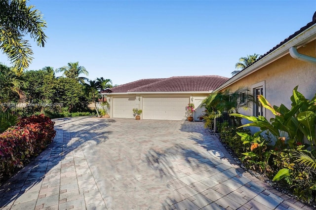 15595 Chandelle Pl, Wellington, FL 33414 - view of side of property with stucco siding, decorative driveway, a garage, and a tile roof