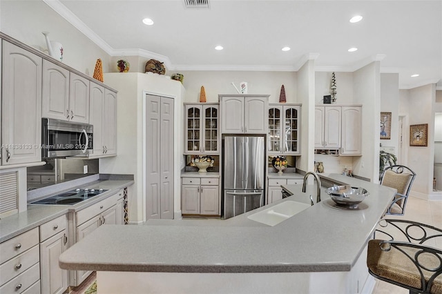 15595 Chandelle Pl, Wellington, FL 33414 - kitchen with appliances with stainless steel finishes, a spacious island, crown molding, a breakfast bar area, and glass insert cabinets