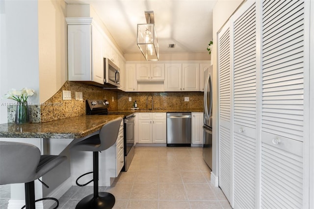 8010 SW 18th Ct Unit 1-8, Davie, FL 33324 - kitchen featuring appliances with stainless steel finishes, decorative backsplash, light tile patterned floors, white cabinetry, and a kitchen bar