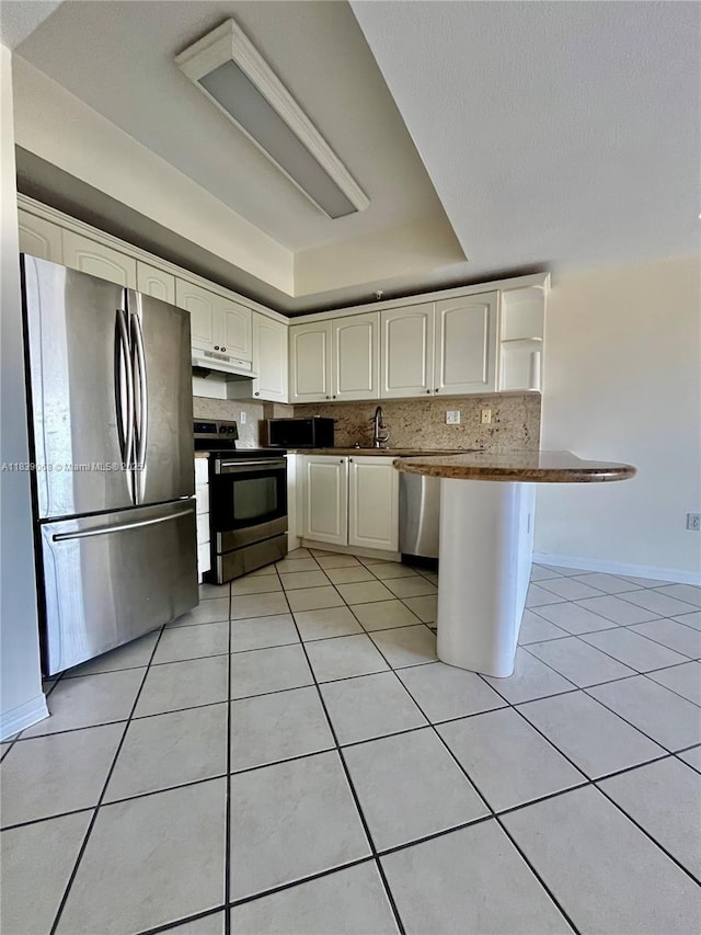 3500 Coral Way Unit 913, Miami, FL 33145 - kitchen featuring stainless steel appliances, under cabinet range hood, a peninsula, light tile patterned floors, and tasteful backsplash