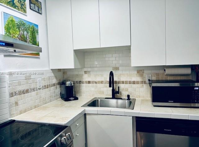 2899 Collins Ave Unit 1504, Miami Beach, FL 33140 - kitchen featuring appliances with stainless steel finishes, white cabinetry, light countertops, and modern cabinets