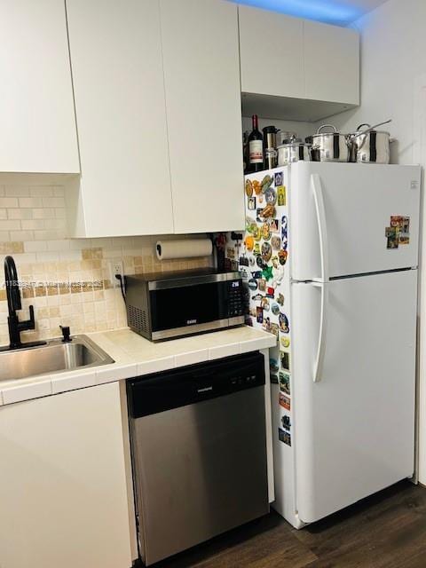 2899 Collins Ave Unit 1504, Miami Beach, FL 33140 - kitchen with stainless steel appliances, dark wood-type flooring, white cabinets, and decorative backsplash
