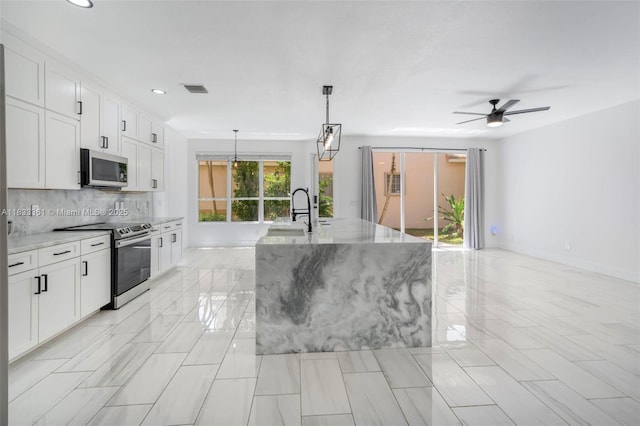 5050 Greenwich Preserve Ct, Boynton Beach, FL 33436 - kitchen with stainless steel electric range oven, light stone counters, a ceiling fan, white cabinets, and recessed lighting