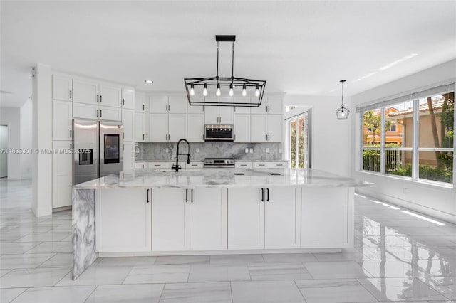 5050 Greenwich Preserve Ct, Boynton Beach, FL 33436 - kitchen featuring appliances with stainless steel finishes, white cabinets, backsplash, a large island with sink, and light stone countertops