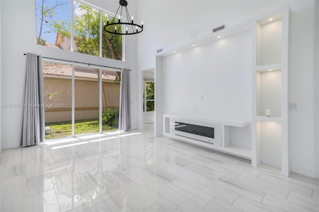 5050 Greenwich Preserve Ct, Boynton Beach, FL 33436 - unfurnished living room with a high ceiling, a chandelier, built in shelves, marble finish floors, and a fireplace