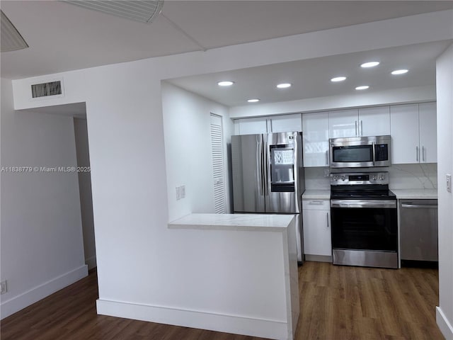1440 Brickell Bay Dr Unit 307, Miami, FL 33131 - kitchen with appliances with stainless steel finishes, wood finished floors, light countertops, white cabinetry, and recessed lighting